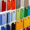 A display wall featuring rows of colorful paint or material samples in various shades, arranged neatly with each sample attached by a round wooden peg.